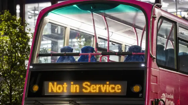 A pink double decker bus with "Not in Service" on it's display