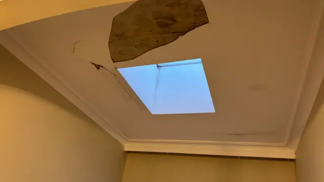 a ceiling damaged near a skylight window