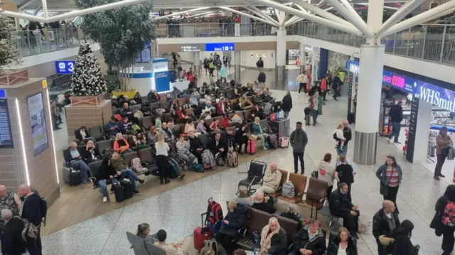 Many people with suitcases and bags in Bristol Airports waiting for flights