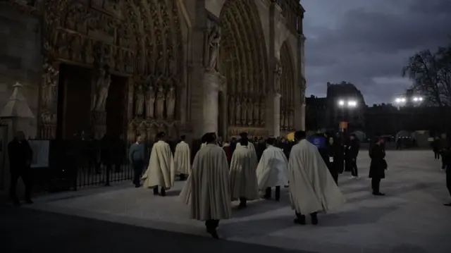 Guests arrive at Notre-Dame for reopening ceremony. In the picture a group of members of the armed forces wearing a white cloak and black hats