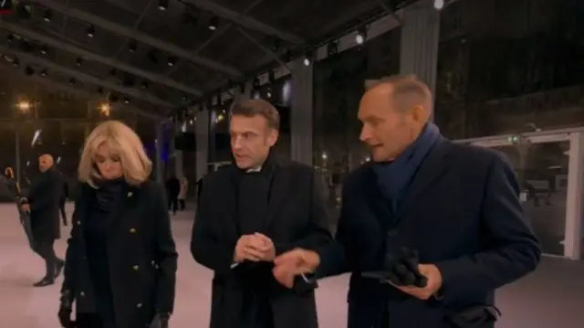 Brigitte Macron in black coat and leather gloves, Emmanuel Macron (C) in black coat and scarf arrive at Notre-Dame for reopening ceremony