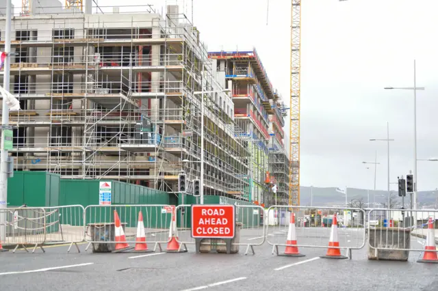 A building site with a barricade in front of it with a sign saying 'road closed ahead'