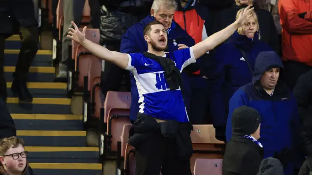 A Birmingham fan sings with his arms outstretched at Oakwell