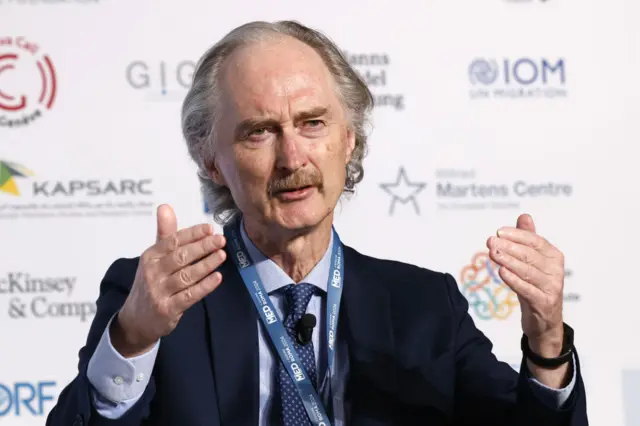 UN envoy to Syria Geir Pedersen gesturing with his hands, shot from mid chest up, wearing dark suit and tie with conference poster behind him. Pic taken 27 Nov