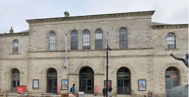 A brown brick theatre building with posters advertising shows