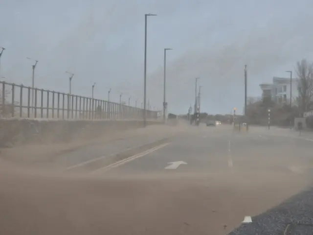 Sand which has blown onto the road in Minehead. The landscape is dusty and visibility is bad.