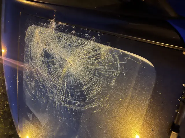 Smashed windscreen of car after being hit by concrete ridge tile