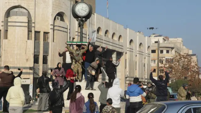 Rebel fighters and people celebrate in Homs after Syria's army command notified officers on Sunday that President Bashar al-Assad's 24-year authoritarian rule has ended