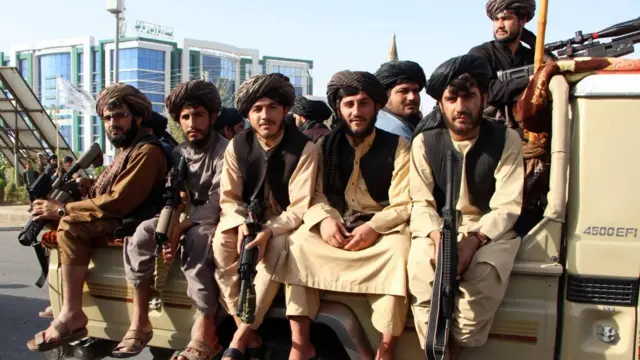 Taliban members in Afghanistan seated on a vehicle, holding guns