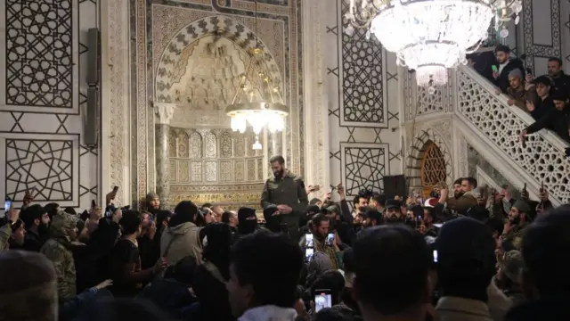 Crowds of people stand to watch Jawlini inside the mosque - many take photos or videos on their phones