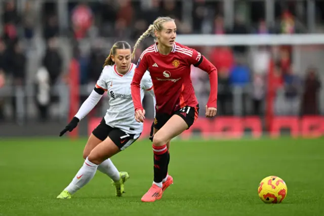 Millie Turner of Manchester United runs with the ball under pressure from Cornelia Kapocs of Liverpool