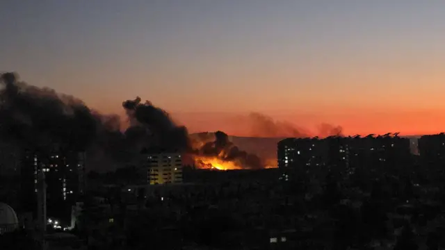 Picture of Damascus skyline with fire and smoke seen in distance