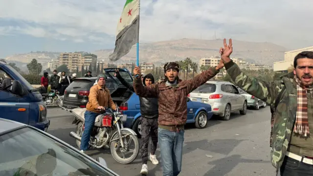 People celebrating while holding a Syria opposition flag