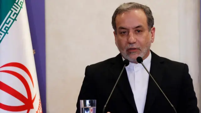 Iranian Foreign Minister Abbas Araghchi in suit and shirt speaking into a microphone