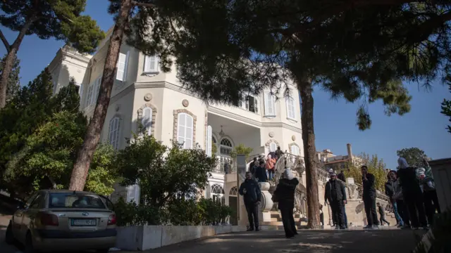 People walk in front of the presidential palace in Damascus, Syria