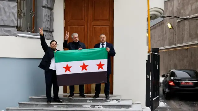 Members of Syrian diaspora pose with opposition lag outside embassy of Syria in Moscow