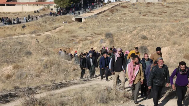 People walk towards the Sednaya prison, dubbed by Amnesty International as the 'Human Slaughterhouse', near Damascus, Syria