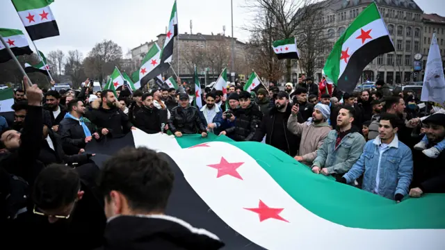 People carry a huge Syrian opposition flag as they gather at Oranienplatz square, after Syrian rebels announced that they have ousted Syria's Bashar al-Assad, in Berlin