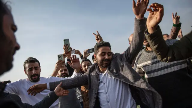 Several men dance with their arms in the air as they celebrate the overthrow of Syrian President al-Assad, in Damascus, Syria