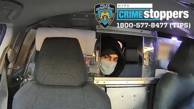 Footage shows a masked person of interest sitting in the back of a taxi, looking directly into the camera