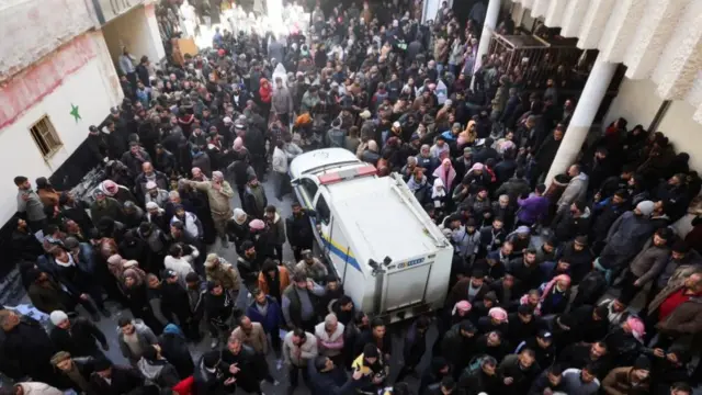 A large group of people gathered around a white van