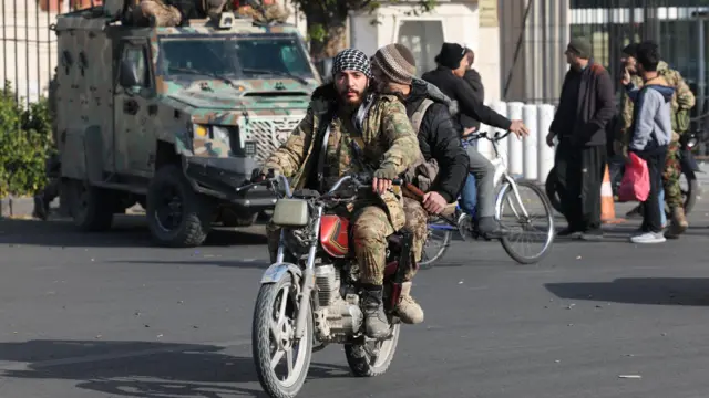 Rebel fighters ride a motorbike through the streets