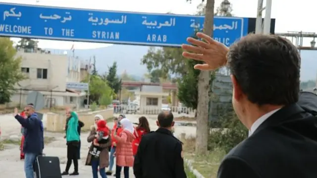 A man waves goodbye to people crossing the Yayladagi border gate in the Hatay province of Turkey in 2018.