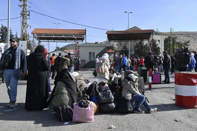 People wait with their belongings after they arrived from Syria, at the Al-Masnaa crossing on the Lebanese-Syrian border,