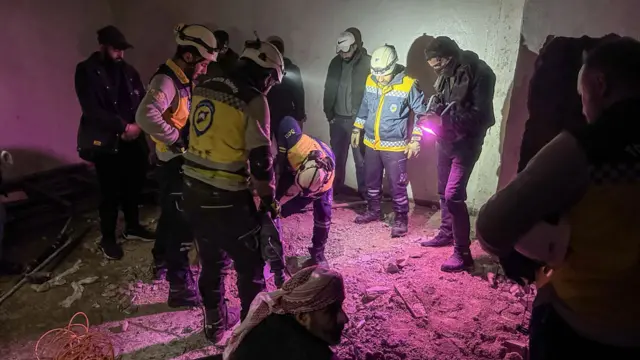 Teams of people, some with helmets, carry out investigations inside the Sednaya military prison