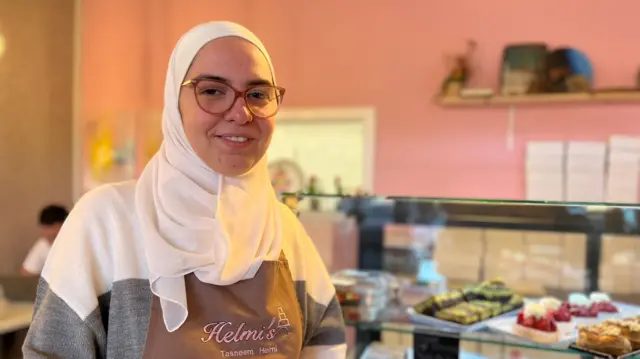 Tasneem Helmi stands before a variety of pastries in her pattiserrie in Milngavie