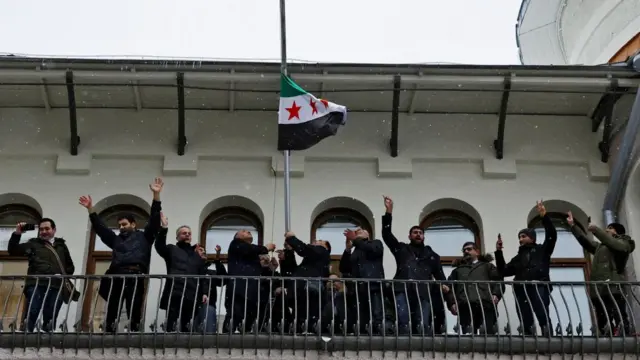 Members of the Syrian diaspora install the opposition flag on the building of the Embassy of Syria in Moscow