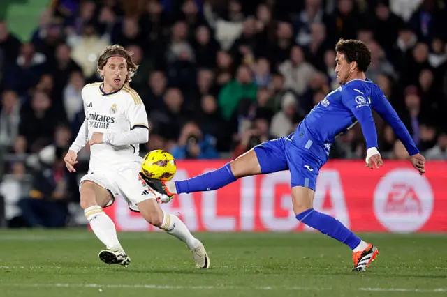 Luka Modric of Real Madrid competes for the ball against Luis Milla