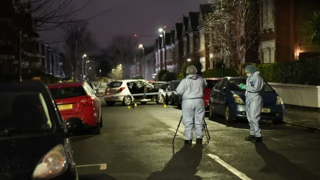 Police stand by an abandoned car at the site of a substance attack in south London