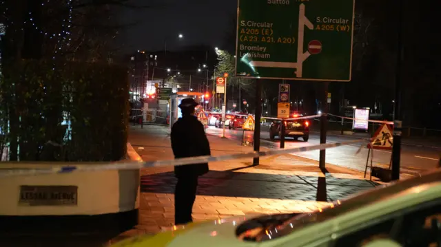 A uniformed officer looks off into the distance near Clapham Common