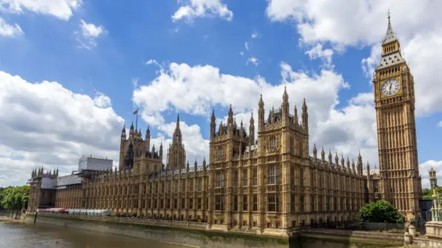 House of Commons and Palace of Westminster next to Thames river in London.