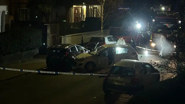 Forensic experts search an abandoned car on a street at night