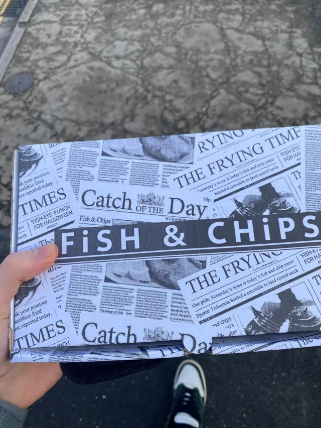 Hand holding box of fish and chips