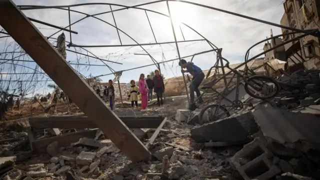 Palestinian children stand among the rubble following an Israeli airstrike on the Rafah refugee camp