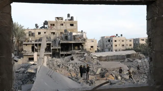 Palestinians inspect the site of an Israeli strike on a house, amid the ongoing conflict between Israel and the Palestinian Islamist group Hamas, in Rafah