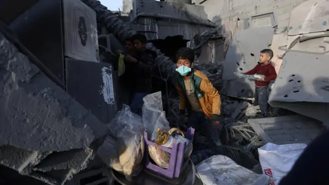 Palestinian children gather belongings from a house that was destroyed in an Israeli strike,