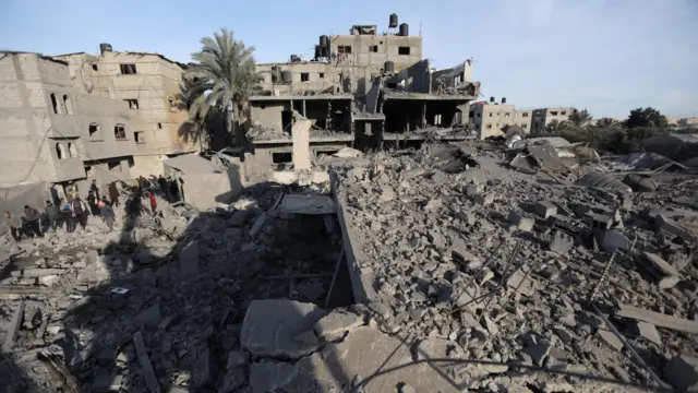 Palestinians inspect the site of an Israeli strike on a house in Rafah