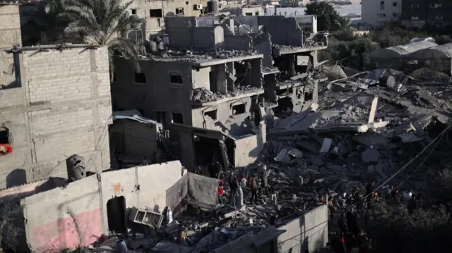 Palestinians inspect the site of an Israeli strike on a house