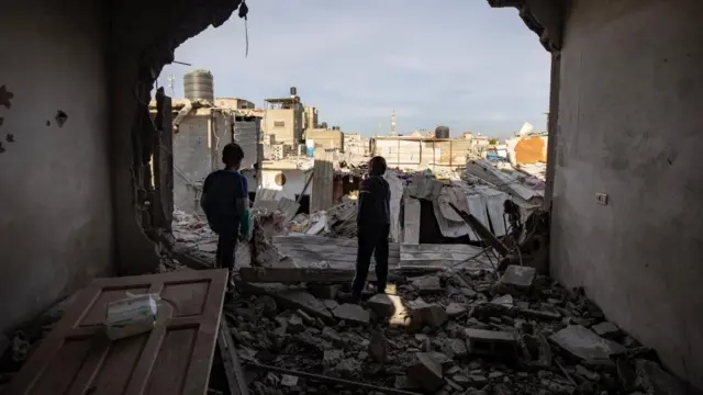 Palestinian children stand inside a destroyed apartment following an Israeli airstrike in Rafah