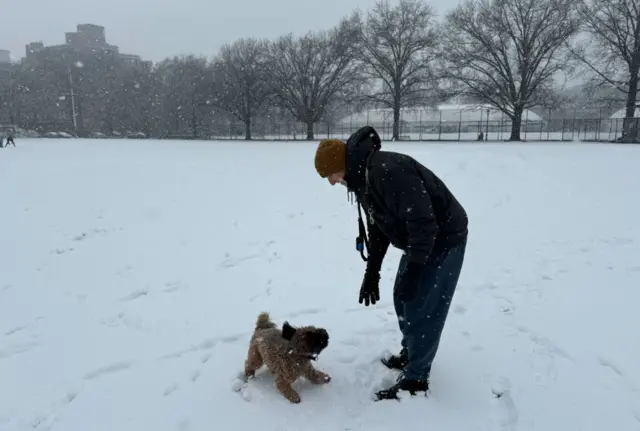 A man and his dog playing in the snow