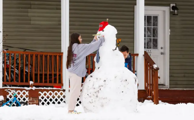 Kids make a snowman outside a house in Tappan, New York, on February 13, 2024