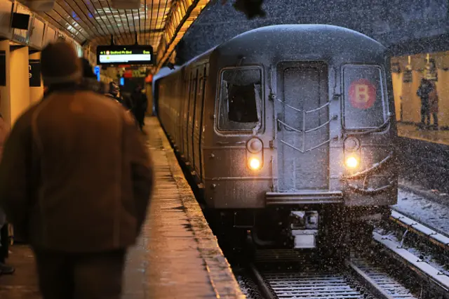 A snowy train arrives at a station in NYC on Tuesday morning