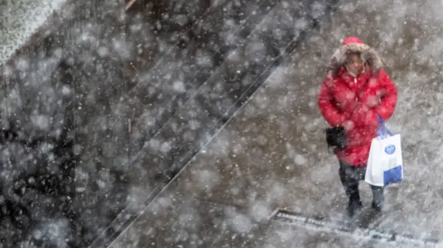 A person standing in the snow wearing a red coat