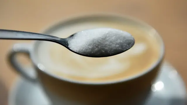 A cup of coffee and teaspoon of sugar