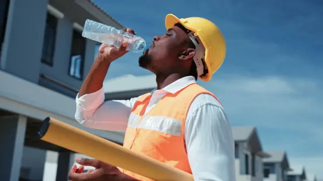 Repair man drinking water outside house