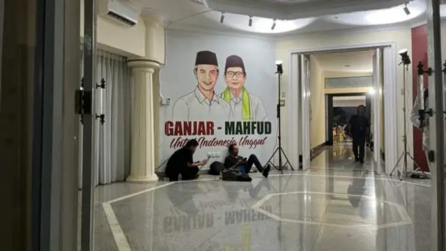 The near-deserted scene in the lobby, with a poster of Ganjar-Mahfud behind two men